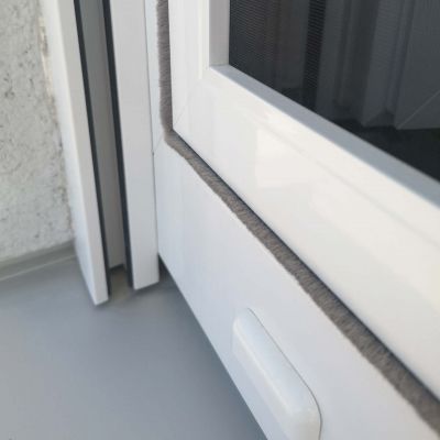 Fliegengitterrahmen am Fenster, man sieht die Bürste